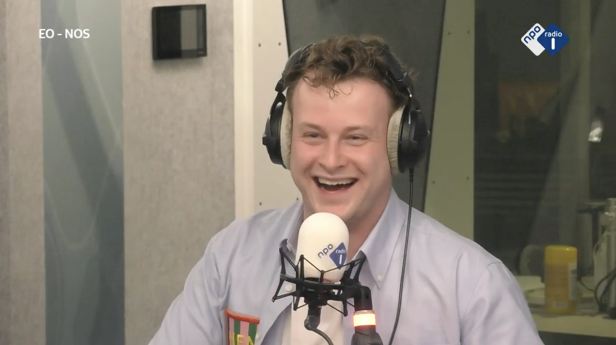Pieter Busman lachend met koptelefoon achter de microfoon in de studio van NPO Radio 1